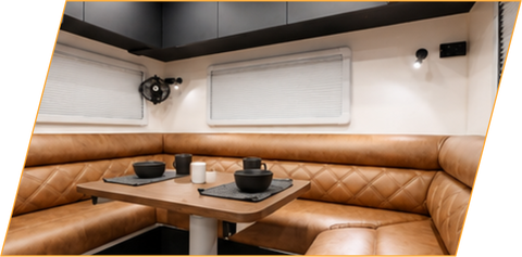 Club lounge with upholstered seating around a table inside the caravan