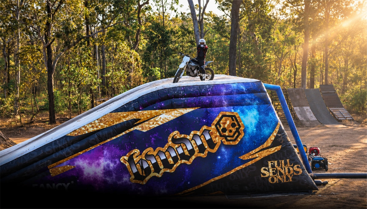 FMX rider standing with a motorcycle on the Limitless FMX airbag landing at sunset