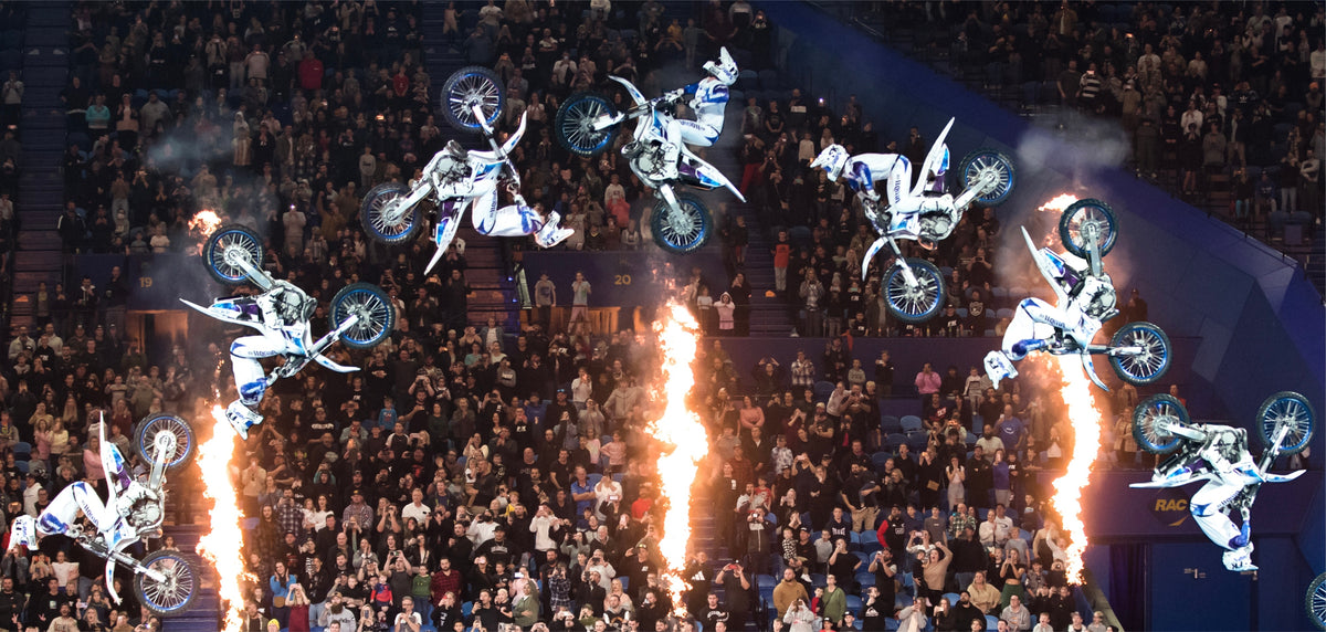 Sequence photograph of Pat Bowden performing a double backflip above an arena crowd with flame effects.