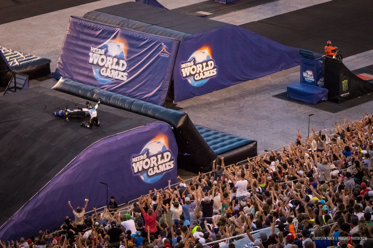 Pat Bowden celebrating beside his motorcycle as the Nitro World Games crowd raises their arms.